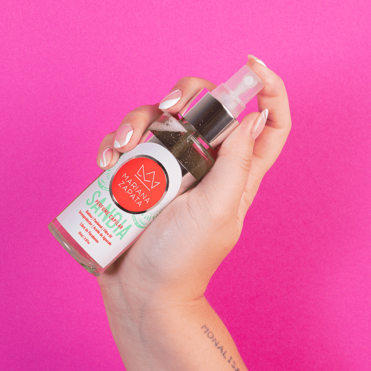 Perfume capilar del Kit Fuerza Capilar en mano, fondo rosa – By Mariana Zapata
