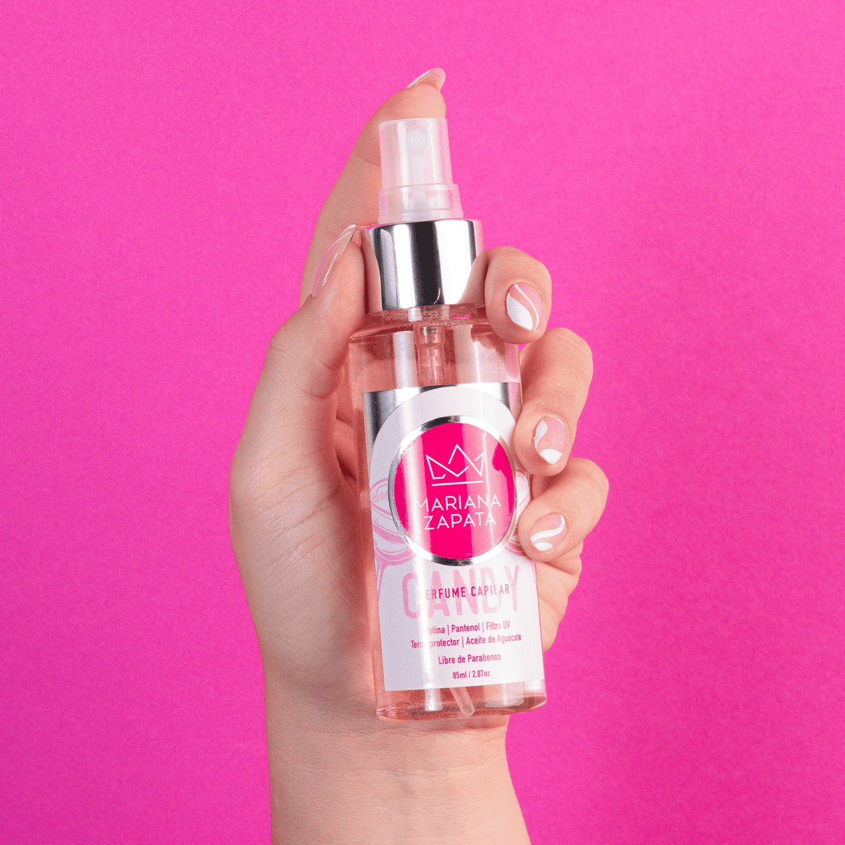 Perfume capilar del Kit Fuerza Capilar en mano, fondo rosa – By Mariana Zapata