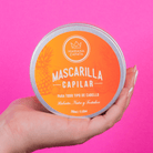Mascarilla Capilar abierta en mano, fondo rosa – By Mariana Zapata