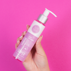 Shampoo Extra Crecimiento tamaño viajero en mano, fondo rosa – By Mariana Zapata